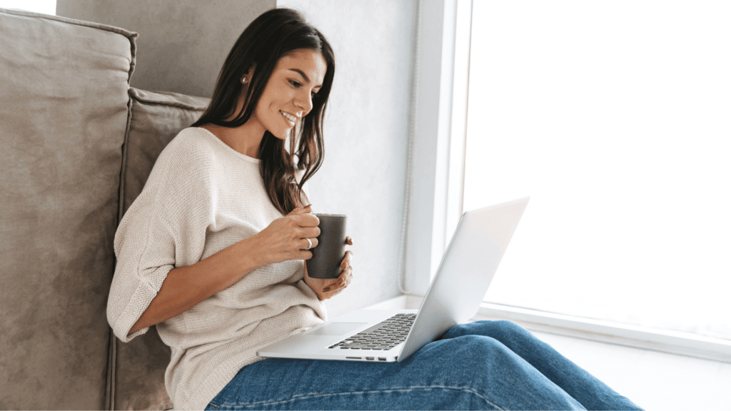 a person sitting on a couch with a laptop and a cup of coffee